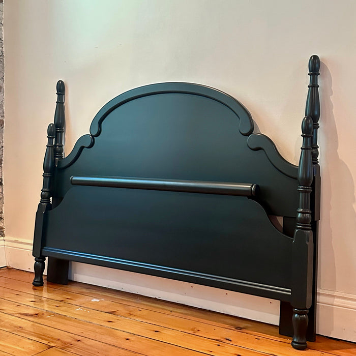 Dark green wooden bed frame against a white wall