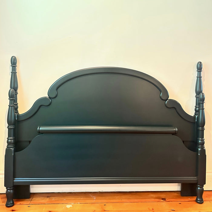 Dark Green wooden bed frame with spindle design against a white wall.