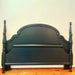 Dark Green wooden bed frame with spindle design against a white wall.