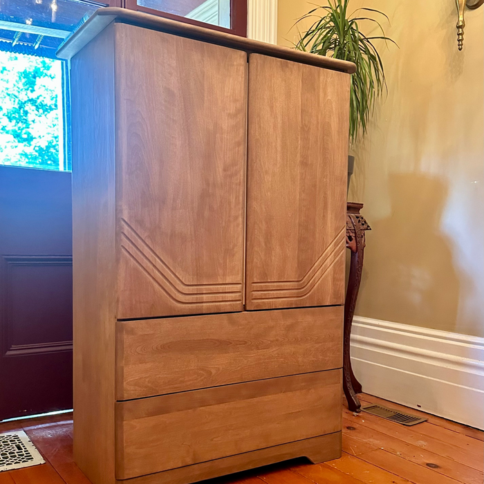 Wooden wardrobe with two doors and two drawers on a wooden floor.
