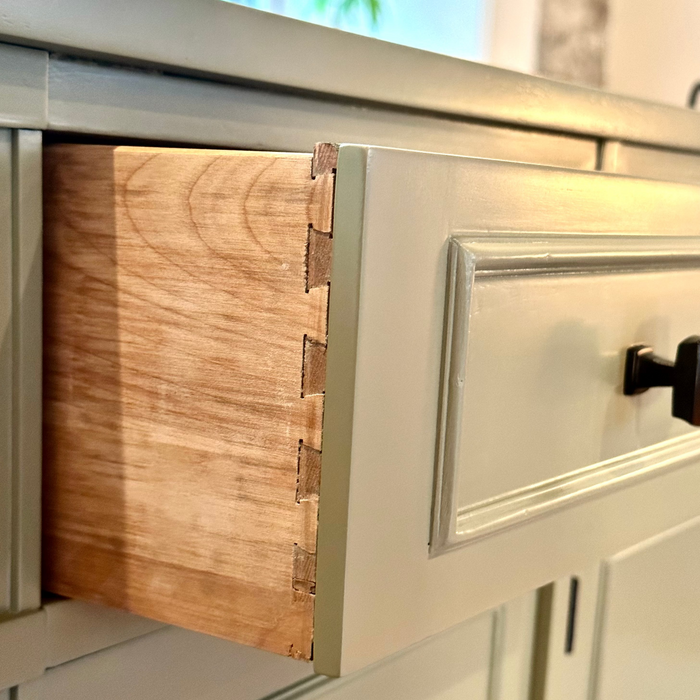 Close-up of a wood sideboard drawer with dovetail joinery.