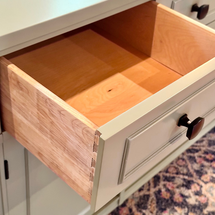 Open wooden drawer in a sideboard  with a patterned rug in the background