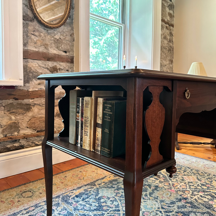 Wooden desk with books against a stone wall and window