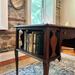 Wooden desk with books against a stone wall and window