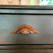 Decorative wood handle on a wooden surface with a mirror and window in the background.